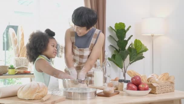 家庭で一緒に台所で娘と一緒に料理やダンスのためのエプロンのスリッシュな小麦粉を身に着けている母親とアフリカ系アメリカ人の家族 楽しさと遊び心のある食べ物を準備親と小さな子供 — ストック動画