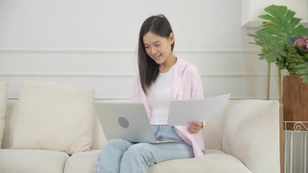 年轻的亚洲女商人在笔记本电脑上工作 在家里看图表和报告 在纸上赚钱 女商人看投资和收入 信息统计数据 — 图库视频影像