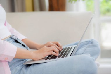 Closeup hands business woman work from home with laptop computer online to internet on sofa in living room, freelance girl using notebook sitting on couch with comfort and relax, lifestyles concept.