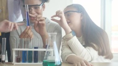 Genç öğretmen grup öğrencilerine bilim öğretiyor ve okul laboratuvarında sıvı için kimyasalı açıklıyordu, çocuklar laboratuarda deney bilimi okuyor ve öğreniyor, eğitim konsepti.