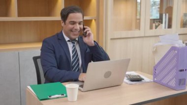 Yönetici ya da yönetici dizüstü bilgisayarla uğraşmakla ve ofisteki başarının yanı sıra akıllı telefonlardan konuşmakla meşgulken, iş adamlarının şirket ve iş konseptinden emin telefon görüşmeleri.