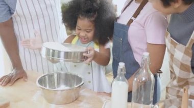African America family wearing apron for cooking bakery or bread with flour together in the kitchen at home, parent and little child preparing food with fun and playful, relationship and hobby.