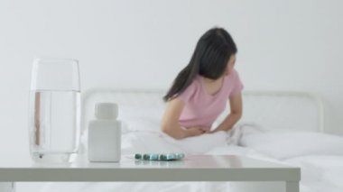 Genç Asyalı bir kadın yatak odasında hasta ve adet ve mide ağrısı, tıbbi ve sağlık konsepti, mide ağrısı, mide ağrısı, bağırsak ya da hastalıklı kabızlık veya hazımsızlık ile evde oturuyor..