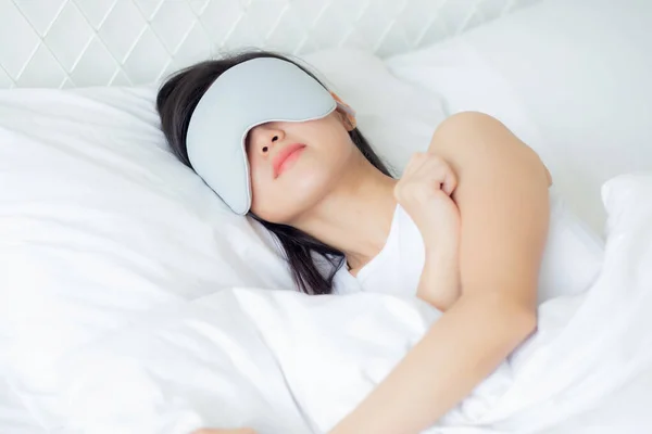 Beautiful young asian woman wearing cover eye and sleeping on bed with head on pillow comfort and happiness in the bedroom at home, girl with relax and leisure for wellness, lifestyles concept.