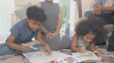 Anne ve babayla mutlu bir aile renkli kalemlerle çizim yapan çocuklar ve evde birlikte oturma odasında, öğrenim için aktivite ve hobi, eğitim kavramı..