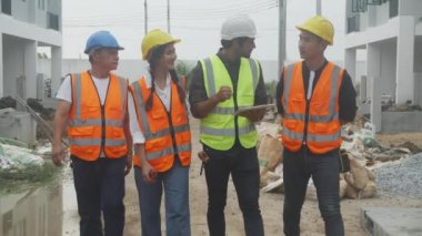 Grup mimarı ve müteahhiti inşaat sahasındaki konut, müteahhit ve işçi tartışması ve planlama, mühendis konsepti için dijital tablet bilgisayarı gezdirip araştırıyorlar..