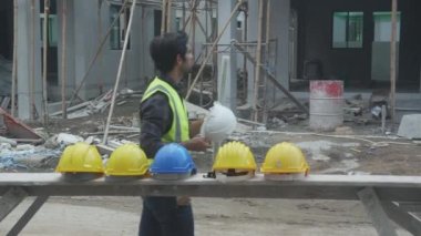 Asyalı genç müteahhit ve işçilerden oluşan bir grup inşaat alanına profesyonel, mimar ve işçilerle birlikte yürüyorlar, inşaat ve takım çalışması, mühendis ve iş arkadaşı ve arkadaşlarıyla birlikte yürüyorlar..