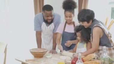 Afro-Amerikan ailesi ve kızı evde anne ve babasıyla yemek pişirmek için taze un için yuvarlanıyorlar, ebeveyn ve küçük çocuk aktiviteleri eğlenceli yemekler hazırlıyorlar..