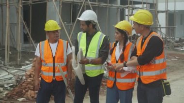 Bir grup müteahhit ve mimar ustabaşıyla birlikte proje planlama projesini işçilere ve proje, inşaat alanı, geliştirme ve yapıya bakmaları için planlama sahasından bahsediyorlar..