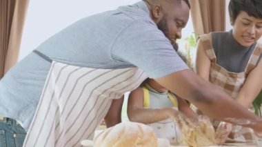 Afro-Amerikan ailesi kızı ile birlikte anne ve babasıyla mutfakta yemek pişirdikleri için taze un, ebeveyn ve küçük çocuk eğlenceli, ilişki ve aktivitelerle yemek hazırlıyorlar..