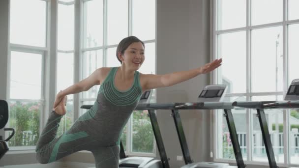 フィットネスジムでストレッチ筋肉の手でヨガを行う若いアジアの女性 家庭でのボディケアのためのヨガと女性のトレーニングの練習 身体の柔軟性とリハビリ スポーツコンセプト — ストック動画