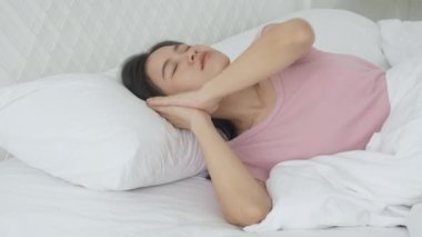 Güzel, genç Asyalı bir kadın yatakta uyuyor yastık üzerinde rahatlık ve mutluluk yatak odasında, rahatlık ve rahatlık, yaşam tarzı ve sağlık konsepti için boş zamanı olan bir kız..