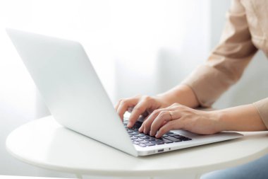 İş kadınlarının yakın çekim elleri ofis masasındaki dizüstü bilgisayarda çalışıyor, masadaki defterde serbest çalışıyor ve daktilo kullanıyor, çevrimiçi öğrenim gören kadın yaşam tarzları, iş kavramı.
