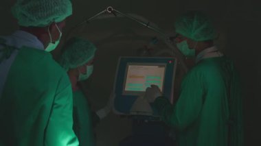 Surgeon team specialist meeting and discussion for treatment patient surgery while using monitor computer together in the operating room at the hospital, doctor conversation, medical concept.