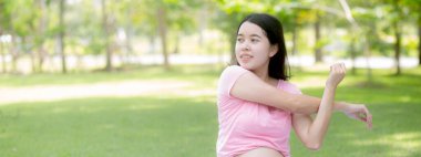 Happiness young asian woman pregnant sitting doing sport exercise with stretch hands muscle for health care at park, mother practicing yoga for leisure in the garden, activity for pregnancy concept.