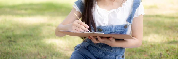 Young asian woman sitting drawing picture with colorful paint brush while leisure in the park on summer, artist and skill with expertise, girl drawing with talent is hobby, lifestyles concept.