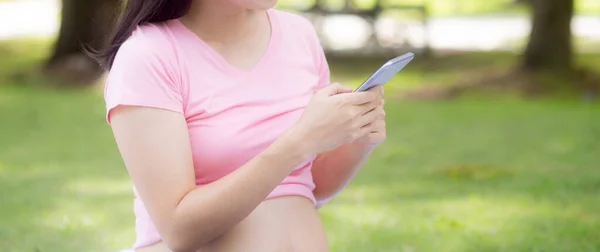 Happiness young asian woman pregnant sitting video call with family on smartphone in the park, woman and positive of health fertility, mom using smart phone on social network online, family concept.