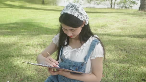 Νεαρή Ασιάτισσα Γυναίκα Κάθεται Σχέδιο Εικόνα Πολύχρωμο Πινέλο Χρώμα Ενώ — Αρχείο Βίντεο