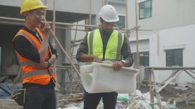 Bir grup müteahhit ve mimar ustabaşıyla birlikte proje planlama projesini işçilere ve proje, inşaat alanı, geliştirme ve yapıya bakmaları için planlama sahasından bahsediyorlar..