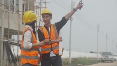 Group team of engineer and architect holding blueprint and explaining using radio communication for planning project real estate, construction site, development and survey structure estate.