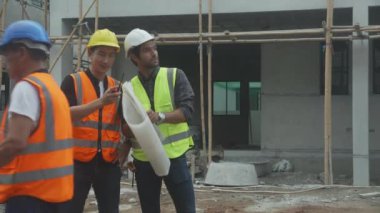 Bir grup müteahhit ve mimar ustabaşıyla birlikte proje planlama projesini işçilere ve proje, inşaat alanı, geliştirme ve yapıya bakmaları için planlama sahasından bahsediyorlar..