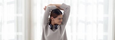 Beautiful young woman waking up in the morning and stretching sitting on bed in the bedroom at home, girl is a cozy with fresh happiness and smile, wellbeing and health concept.
