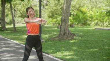 Genç Asyalı güzel bir kadın yazın parkta ısınma ve kas gevşeme egzersizi, bahçede tropik sporla rahatlamak için kız egzersizi, bir kişi, sağlık ve spor konsepti..