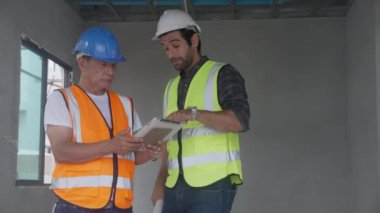 Team of architect or engineer man wearing hardhat looking tablet for inspect and planning construction at construction site, contractor or builder examining project with professional for success.