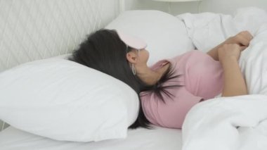 Güzel Asyalı genç bir kadın örtülü göz takıyor ve yatak odasında başı yastıkta uyuyor rahatlık ve mutlulukla, rahatlık ve rahatlık için boş vakti olan bir kız, yaşam tarzı konsepti..