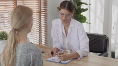 Young woman doctor talking and discussion with patient about disease and illness for diagnostic at clinic, physician explaining and consultation about sick and checkup, medical and insurance concept.