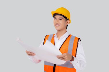 Portrait young asian man is engineer wearing helmet holding and looking blueprint with confident isolated on white background, handsome male is architect or contractor, worker or labor concept.