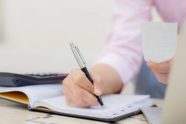 Closeup hands of woman calculating finance household with calculator on desk at home, girl checking bill for saving and planning expenses, debt and loan, tax and accounting, business and financial.