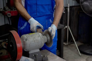 Closeup hands of young man sanding or iron at industrial factory, mechanic working job while polish metal, male having skill built steel with tool, labor and steelworks, industry concept.