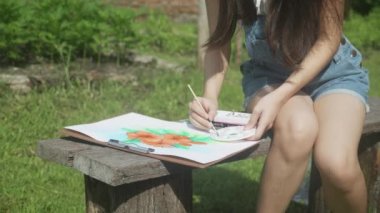 Genç Asyalı kadın renkli boya fırçasıyla resim çizerken yazın parkta boş zamanlarında sanatçı ve uzmanlık becerisi, yetenekli kız çizimi hobi, yaşam tarzı konsepti.