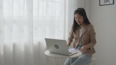 Genç Asyalı iş kadını çevrimiçi video konferansı için dizüstü bilgisayar kullanıyor, iş kadını toplantı için video çağrısı ile çalışıyor ve finans, iletişim konsepti için grafik raporu gösteriyor.
