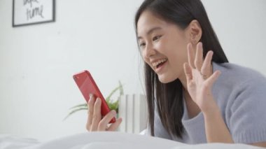 Genç Asyalı bir kadın, internet üzerinden arkadaşlarıyla video konferans için akıllı telefon kullanıyor. İş kadını, sosyal ağla görüşmek için telefon görüşmesi yapıyor. Akıllı telefon, iş ve iletişim kavramı..