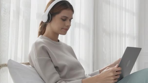 Happy Young Woman Wearing Headphones Listening Music While Using Laptop — Vídeo de stock