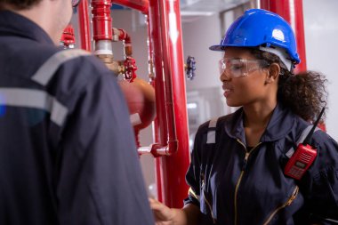 Young woman and man engineer check and examining pipeline and discussion in the factory, mechanic or technician inspector plumber valve and talking together, industrial and maintenance concept.