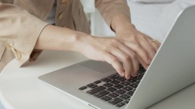 Closeup hands of businesswoman working on laptop computer on desk at home office, freelance looking and typing on notebook on table, lifestyles of woman studying online, business concept.