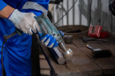Closeup hands of young man sanding or iron at industrial factory, mechanic working job while polish metal, male having skill built steel with tool, labor and steelworks, industry concept.
