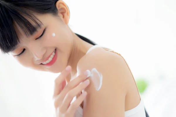 Beautiful young asian woman happy applying cream or lotion with moisturizer to skin on shoulder, beauty asia girl applying skincare with cosmetic makeup for hygiene and wrinkle, skin care concept.