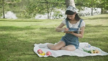 Genç Asyalı kadın renkli boya fırçasıyla resim çizerken yazın parkta boş zamanlarında sanatçı ve uzmanlık becerisi, yetenekli kız çizimi hobi, yaşam tarzı konsepti.