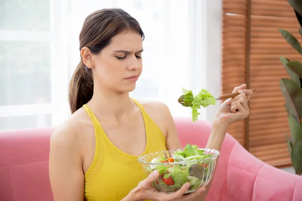 Jovem Caucasiana Sentada Sofá Comendo Salada Legumes Enquanto Sente Desgostosa — Fotografia de Stock