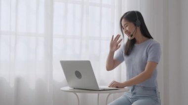 Genç Asyalı kadın arkadaşlarıyla çevrimiçi video konferansı için laptop kullanıyor. İş kadını sosyal ağ, iş ve iletişim konseptiyle görüşmek için video çağrısı yapıyor..