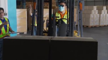 Grup çalışanı ve adam forklift kutusu kullanıyor ya da fabrikadaki depoda nakliye ve dağıtım için ambalaj yapıyor, depoda çalışan, lojistik konsept.