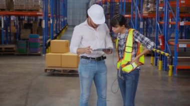 Genç bir kadın müdürle konuşurken fabrikadaki depodaki panoda imzalı belge, patronla raflardaki kargo dağıtımı, nakliye ve lojistik konsept hakkında çalışan tartışması..