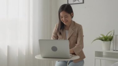 Young asian businesswoman working on laptop computer on desk at home office, freelance looking and typing on notebook on table, lifestyles of woman studying online, business and education concept.