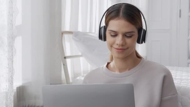 Happy Young Woman Wearing Headphones Listening Music While Using Laptop — 비디오