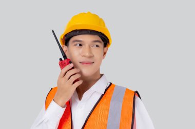 Genç Asyalı adam miğfer takan bir mühendis ve radyoyu beyaz arka planda izole edilmiş, yakışıklı erkek mimar, müteahhit, işçi ya da işçi kavramı ile konuşmak için kullanıyor..