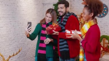 Genç arkadaşlar, Noel arifesinde, Noel arifesinde, Noel arifesinde, bayramında veya tatil konseptinde sosyal medyayı kullanan kadın ve erkek, heyecanlı ve akıllı telefonlardan keyif alarak görüntülü arama yaparlar..